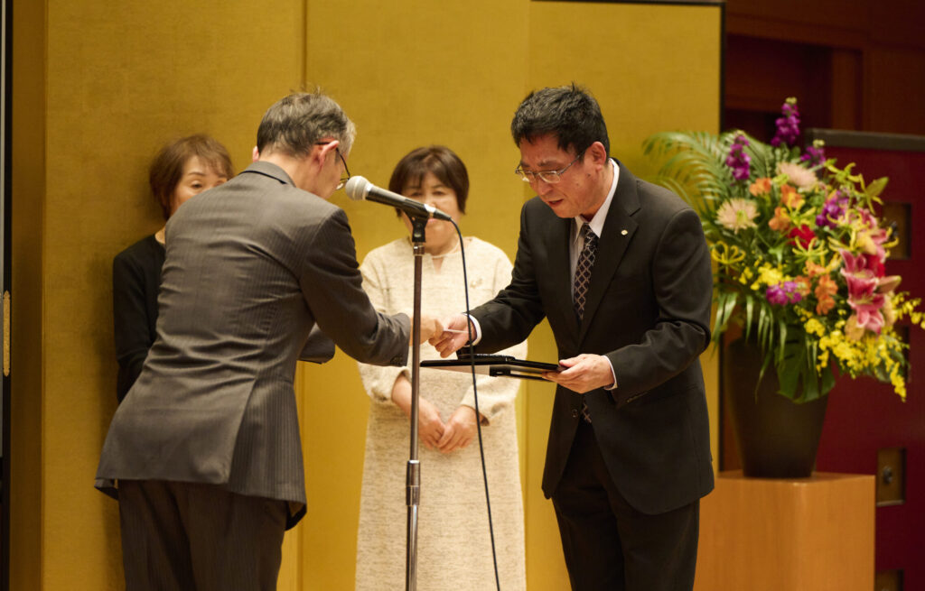 一礼し、西脇社長から表彰楯を受け取る社員