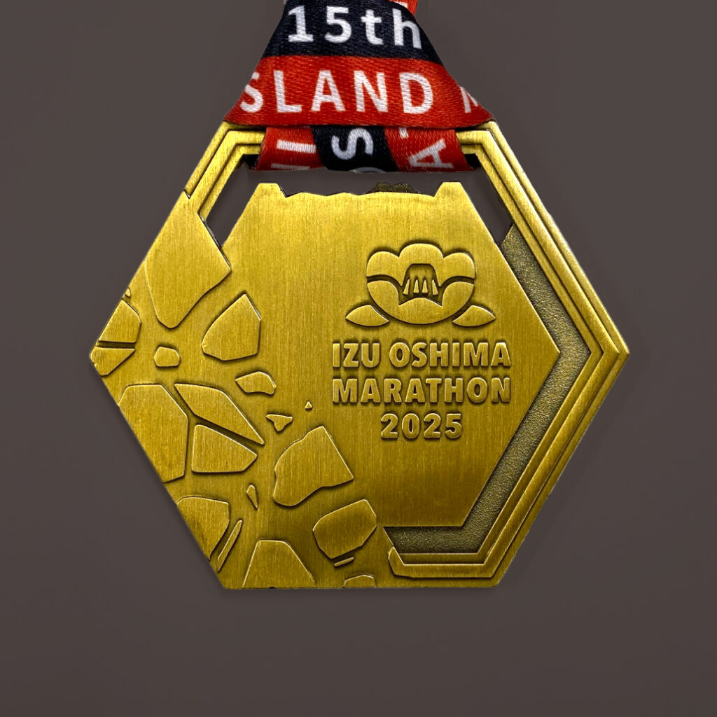 伊豆大島マラソンメダルの表面。柱状節理を模した6角形の形状で玄武岩のモチーフがあしらわれている。