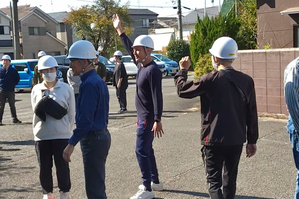 集合場所で点呼を行う避難訓練中の社員たち